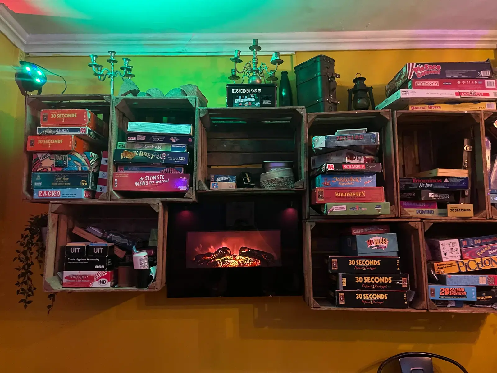 De spelletjeswand bij Bar Boef. Houten kisten vol dozen boven een haard.